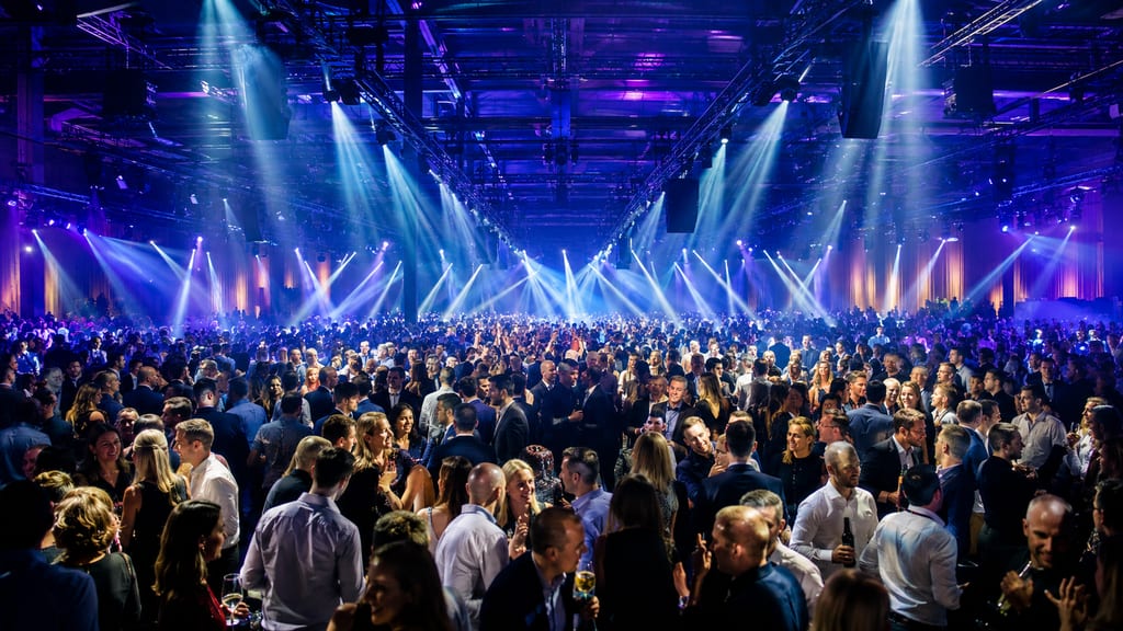 Large crowd fills a venue at a corporate event under blue stage lighting