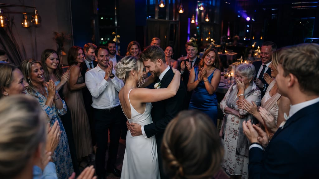 Bride and groom embrace during first dance as guests applaud around them